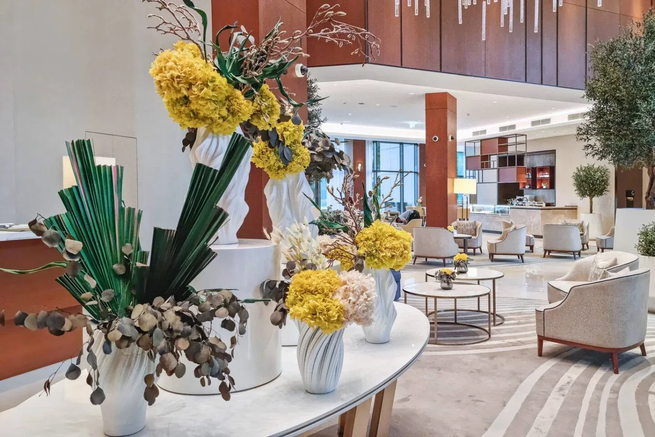 A spacious modern lobby with lounge seating and large floral arrangements.