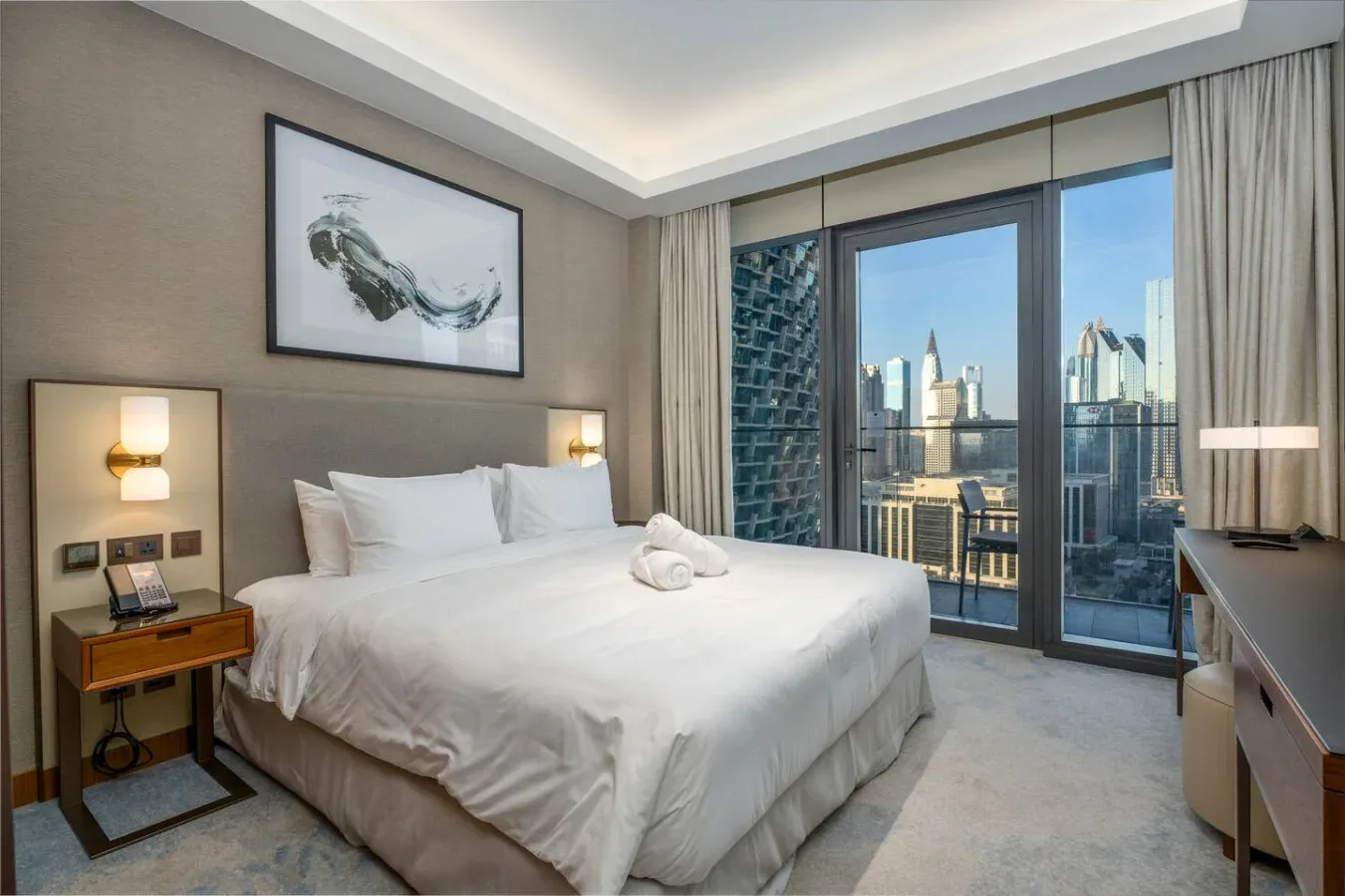 A bedroom with a neatly made bed and floor-to-ceiling windows overlooking the city.