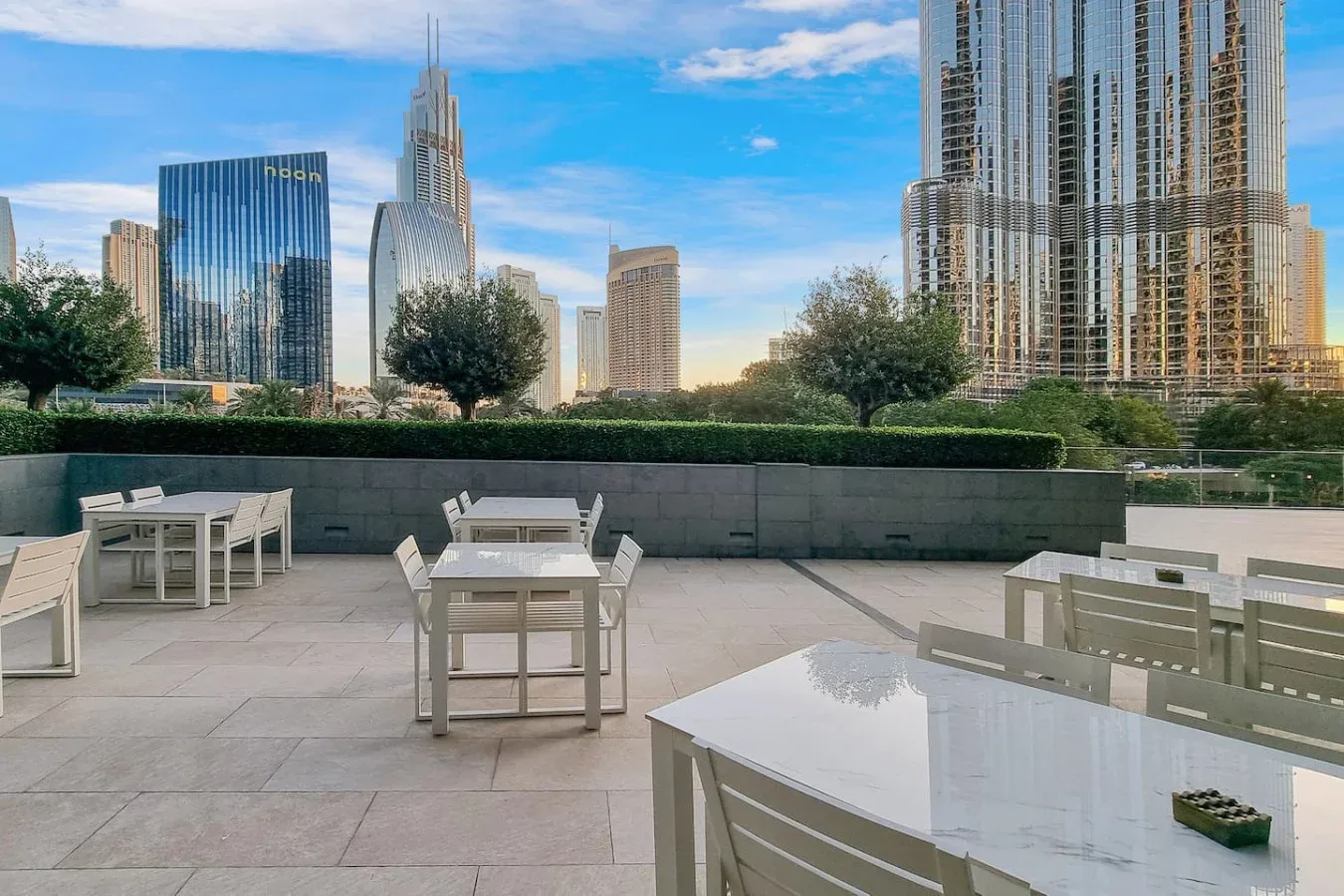 An outdoor terrace with seating overlooks a city skyline.