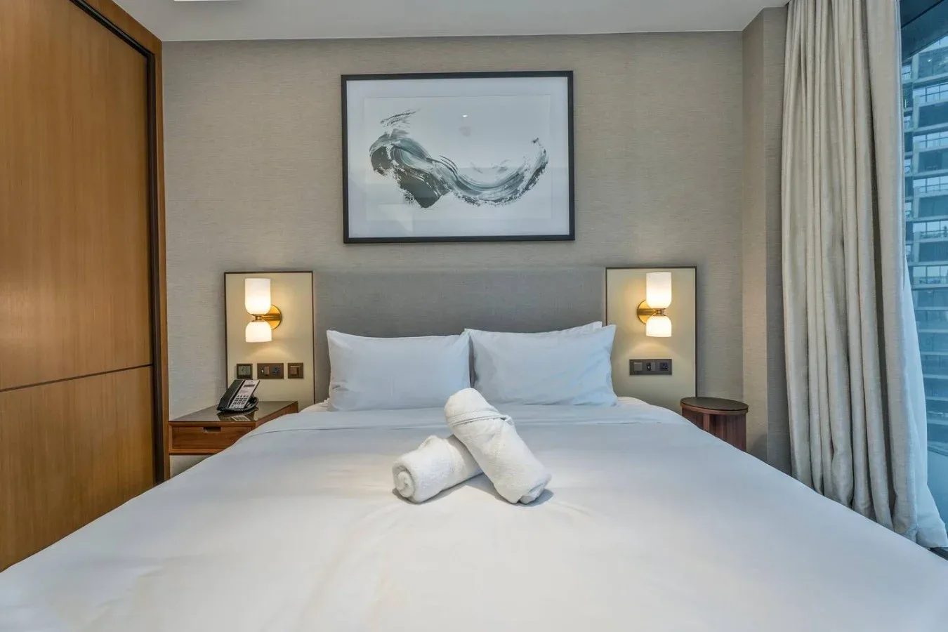 A hotel bedroom with a neatly made bed and folded towels.