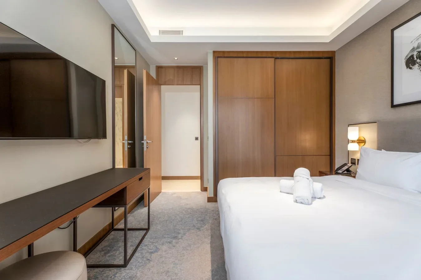 A bedroom with a neatly made bed and a wall-mounted television.