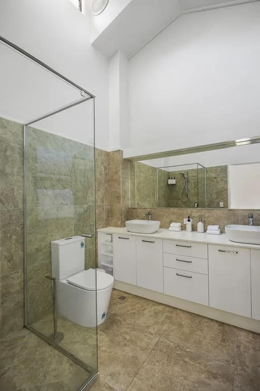 A bright bathroom with a glass shower and white vanity.