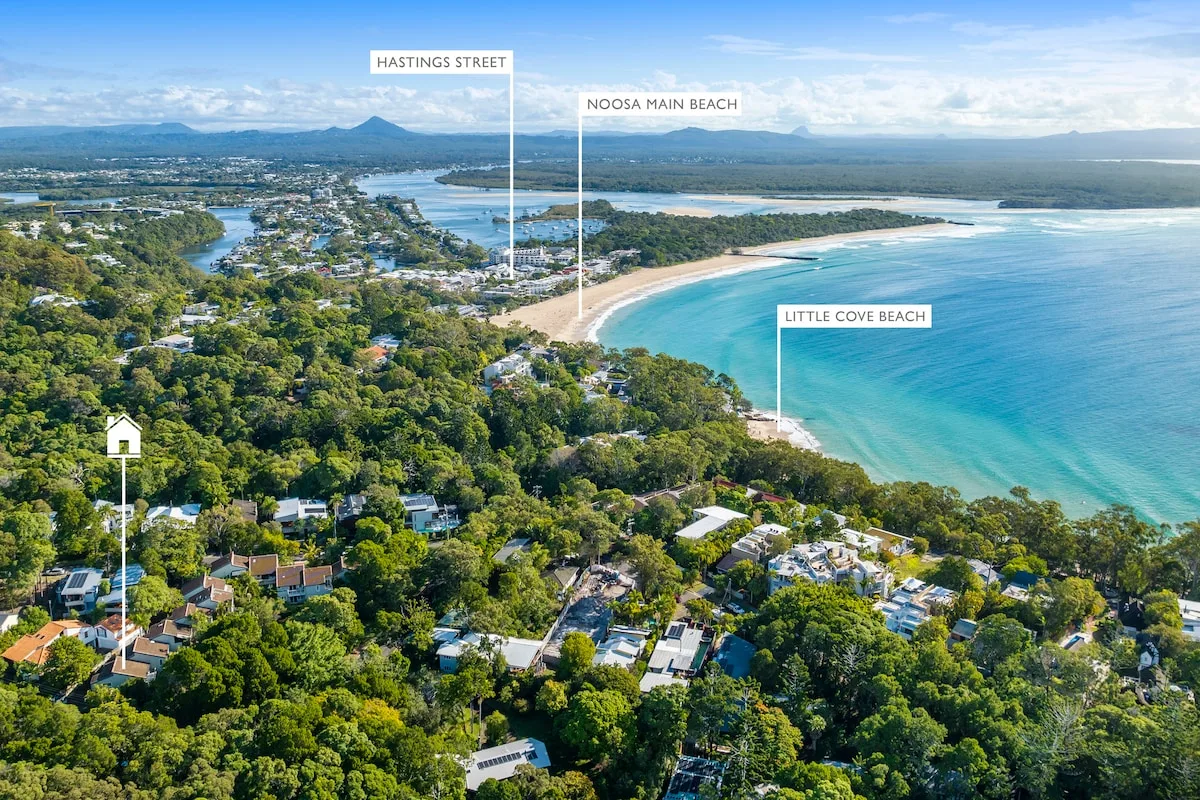 An aerial view of a coastal town beside a curved beach and turquoise water.