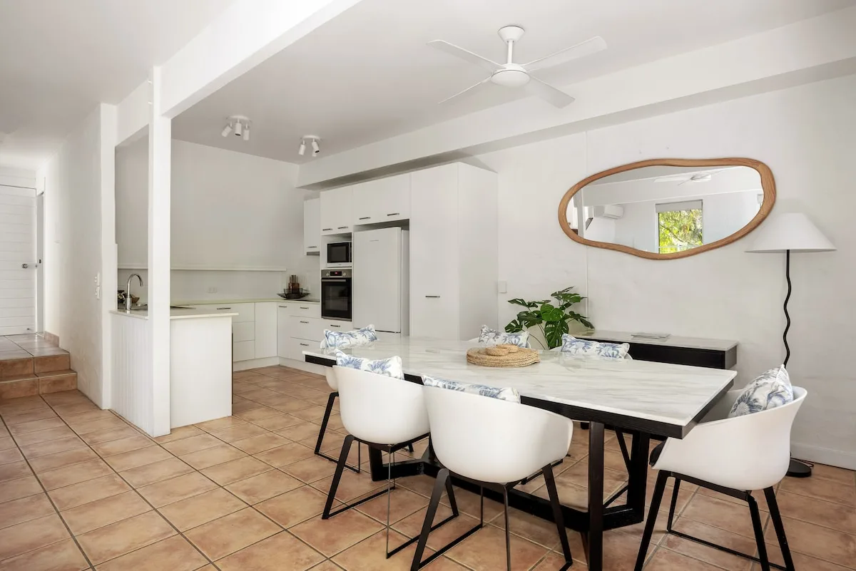 Open-plan kitchen and dining area with a table and white seating.