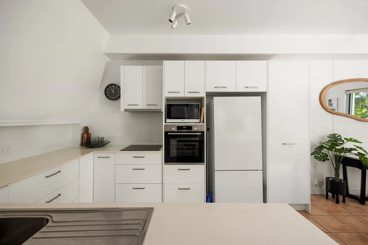 A bright kitchen with white cabinets, a refrigerator, and built-in appliances.