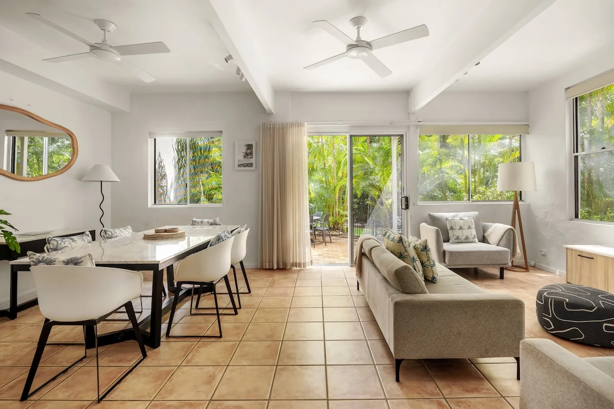 A bright open-plan living and dining area with seating and large windows.