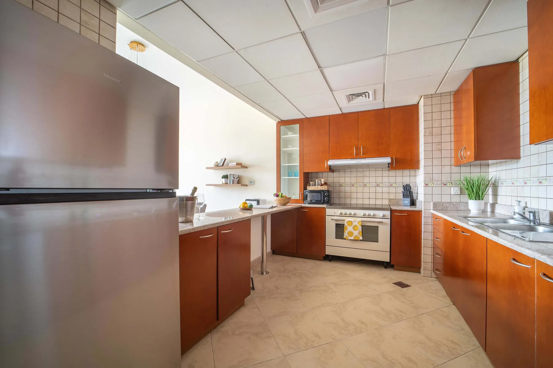 A kitchen with wood-toned cabinets, a refrigerator, and a tiled backsplash.