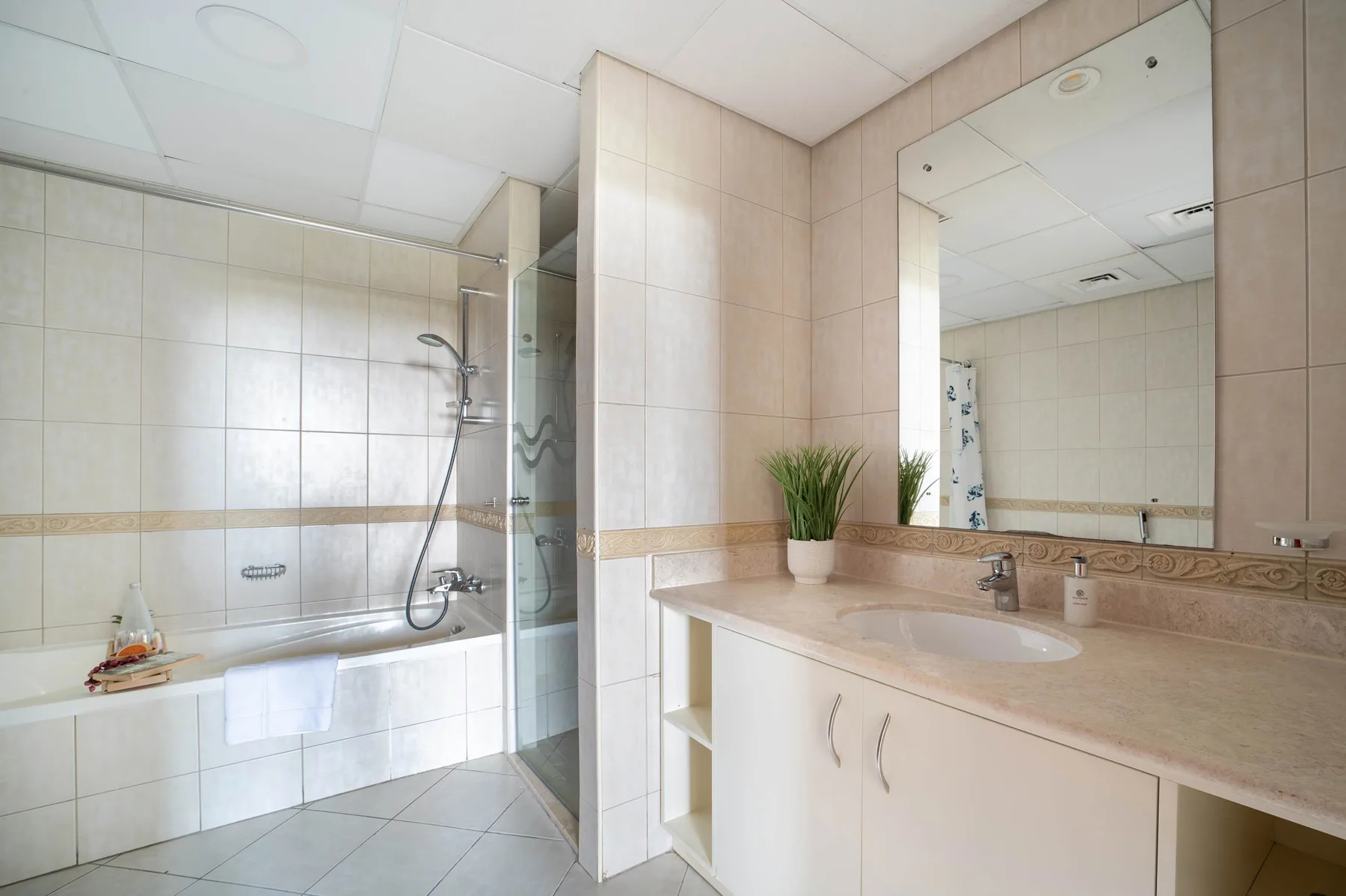 A tiled bathroom with a bathtub, shower, and wide vanity.