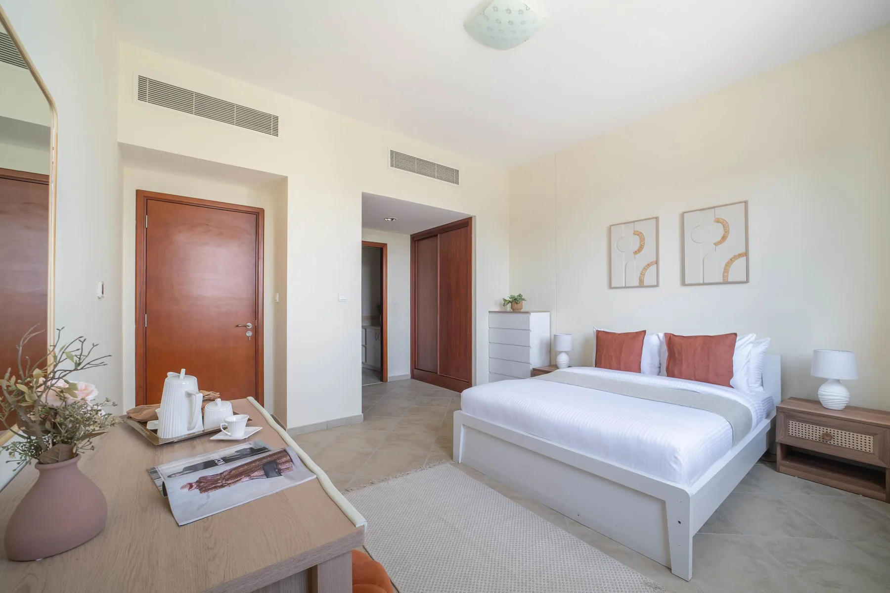 A bright bedroom with a neatly made bed and bedside tables.
