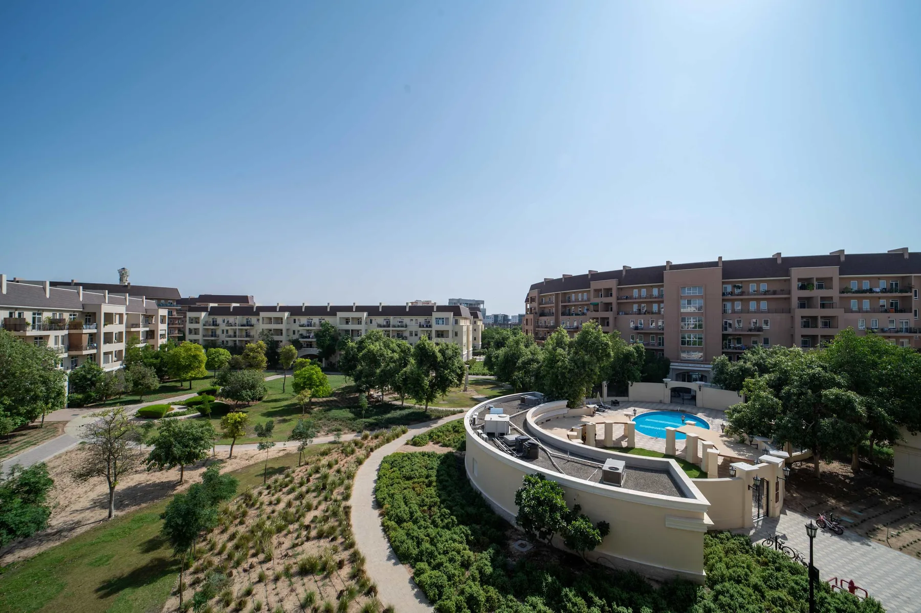 Residential apartment buildings surround landscaped grounds and a curved pool area.