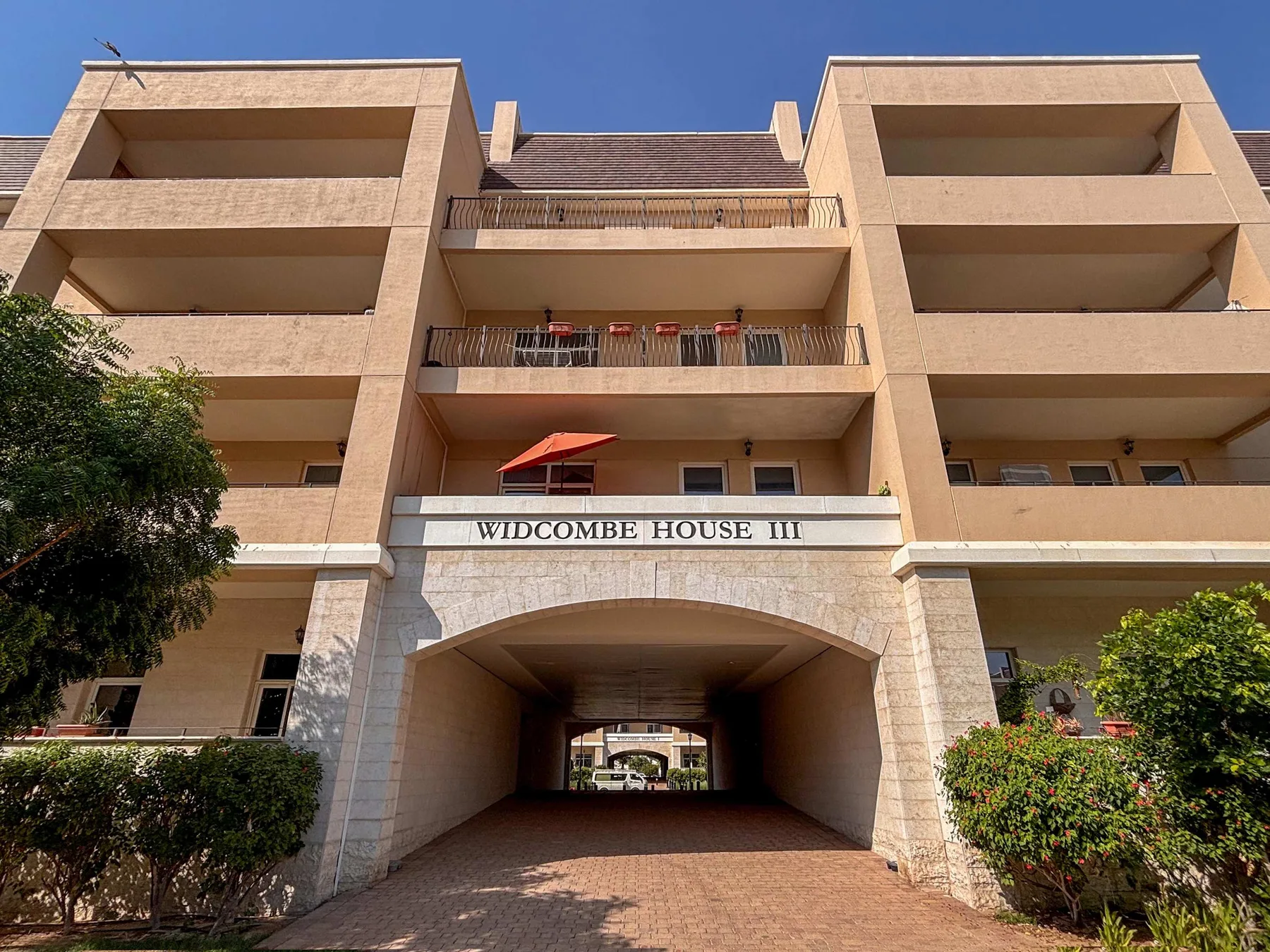 A multi-story building facade with balconies and a covered driveway entrance.
