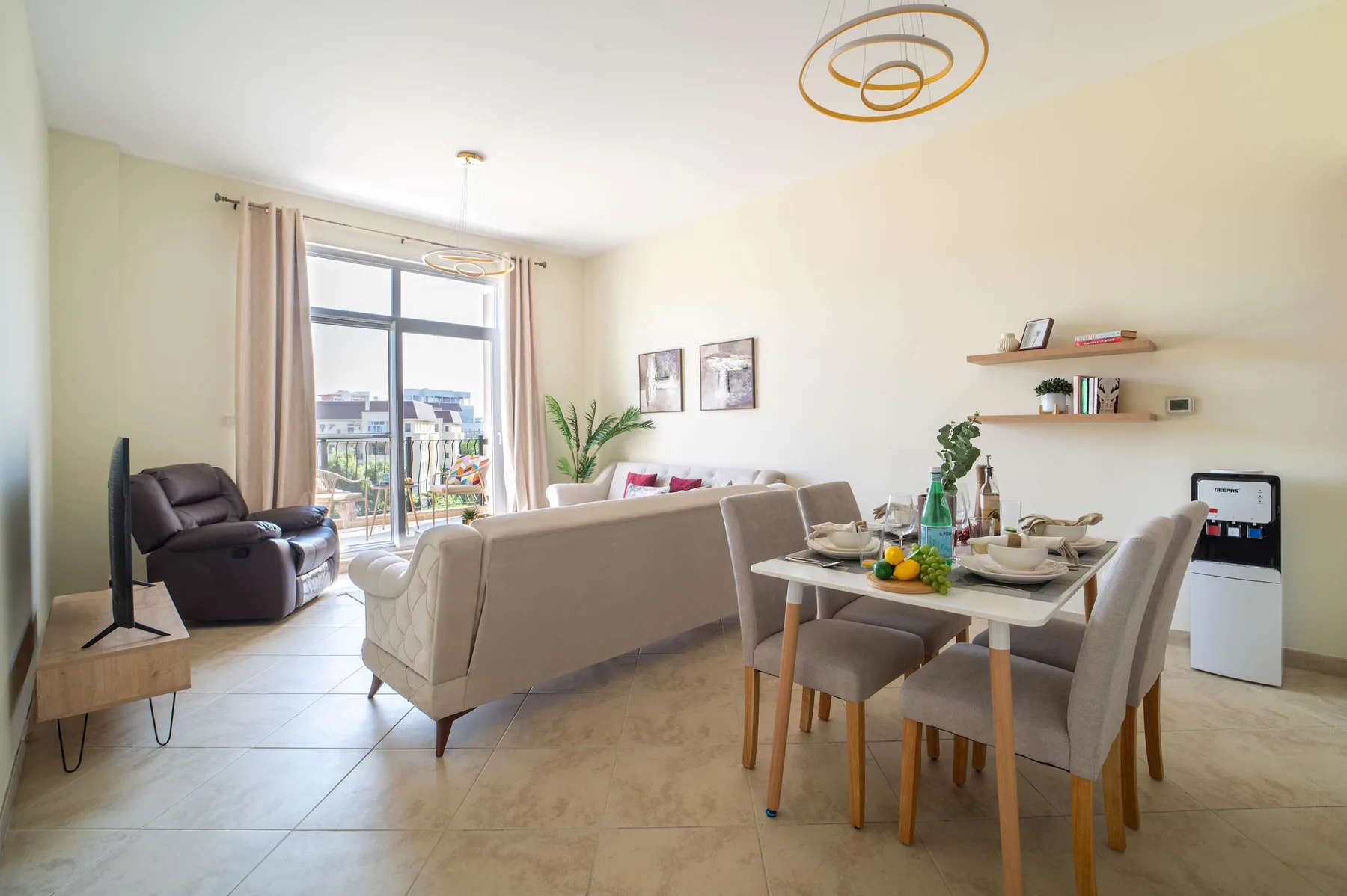 A bright living and dining area with seating, a dining table, and a large window.