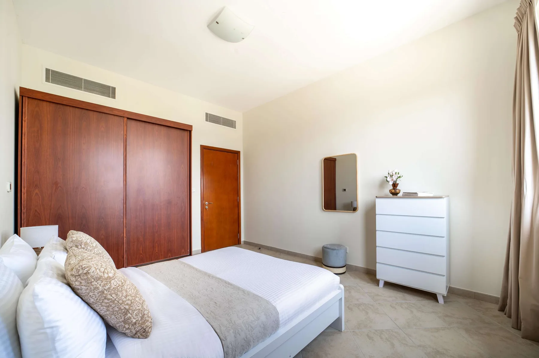 A bedroom with a bed, wooden wardrobes, and a white chest of drawers.