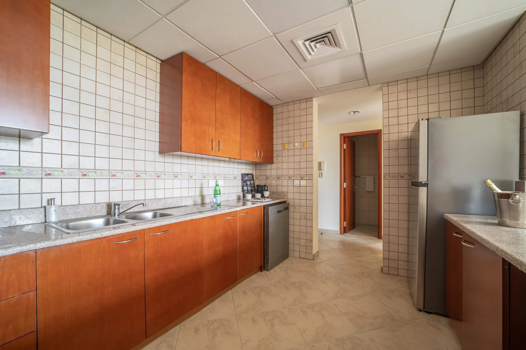 A tiled kitchen with wood-toned cabinets and a long countertop.