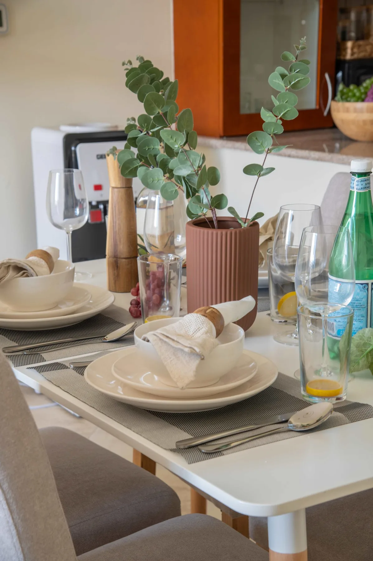 A dining table is set with plates, glasses, and a potted plant.
