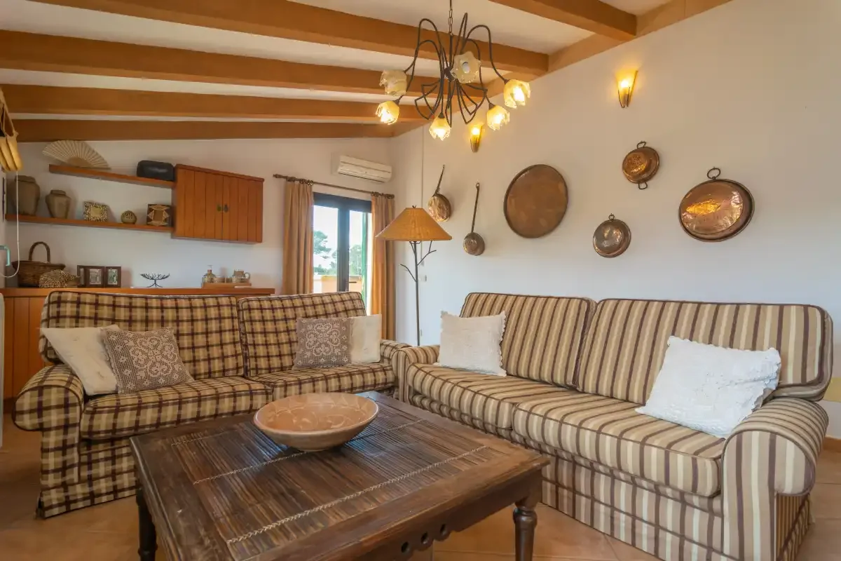 A living room with striped seating, a wooden coffee table, and exposed ceiling beams.