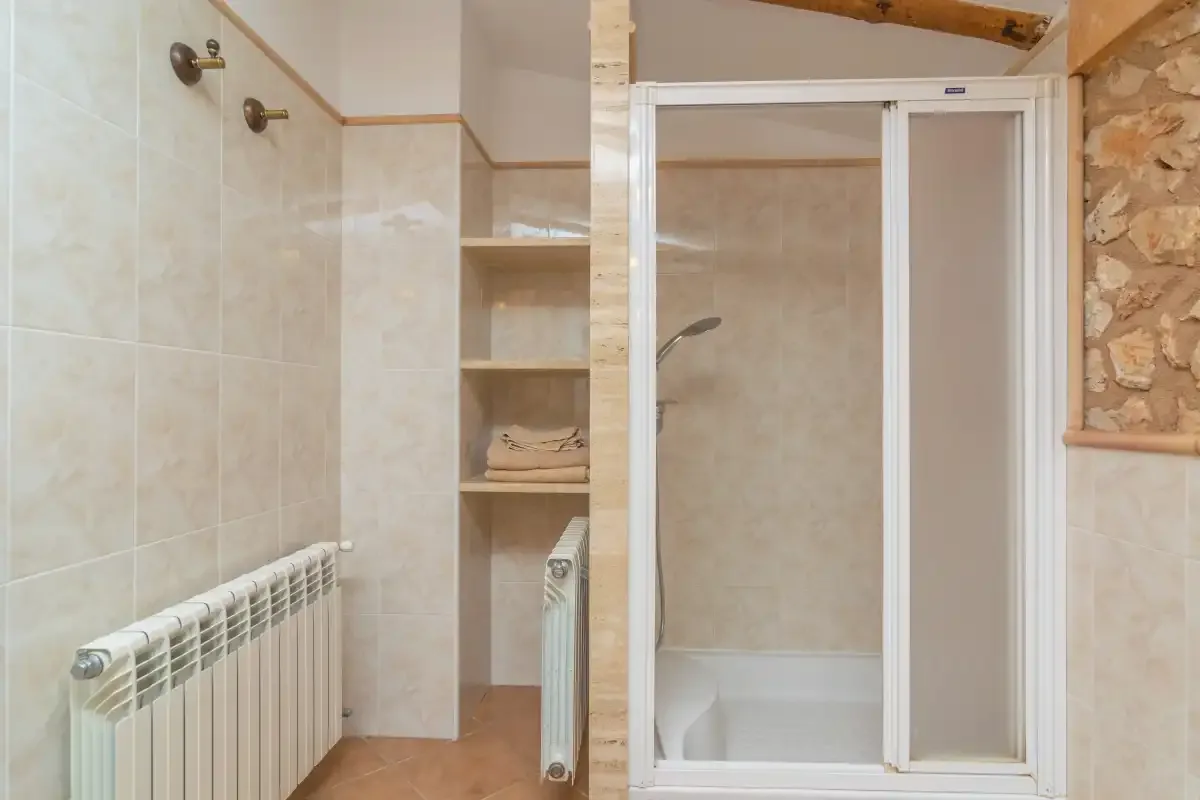A tiled bathroom with a shower and wall-mounted radiator.