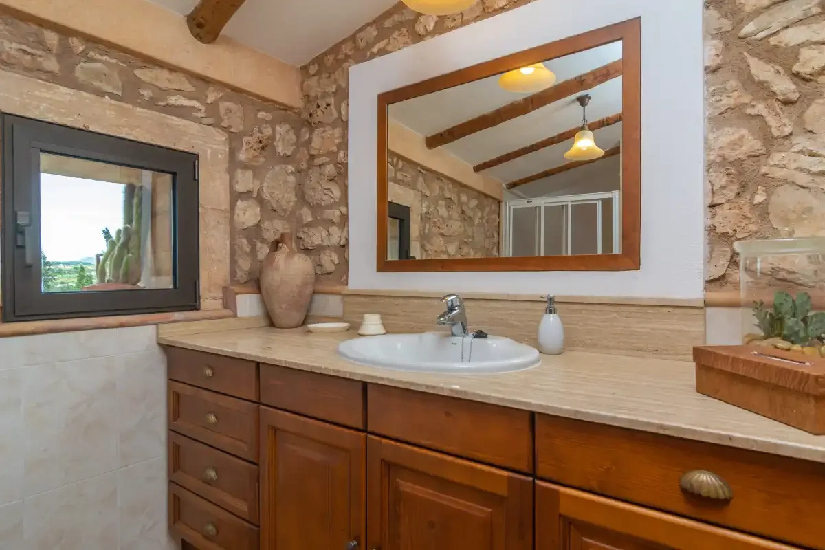 A bathroom vanity with a sink, mirror, and stone walls.