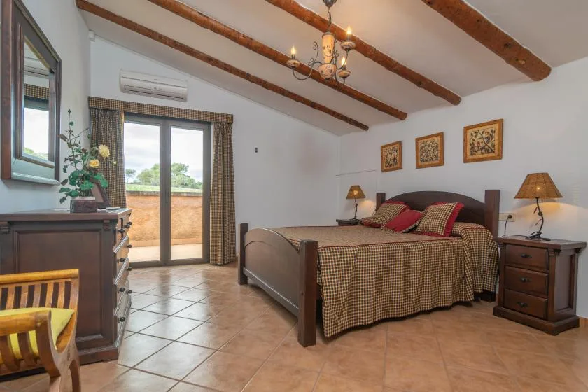 A bedroom with a large bed, bedside tables, and a glass door opening onto a balcony.