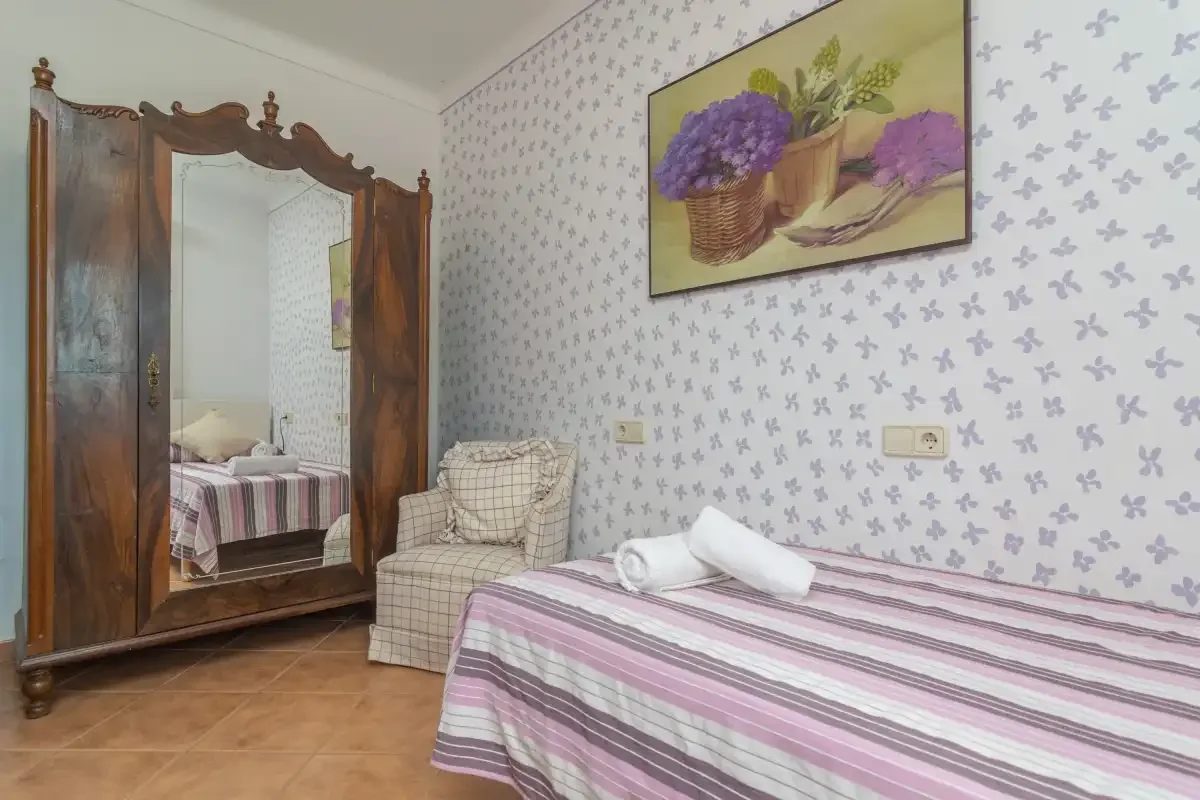 A bedroom with a bed, wardrobe, and patterned wallpaper.