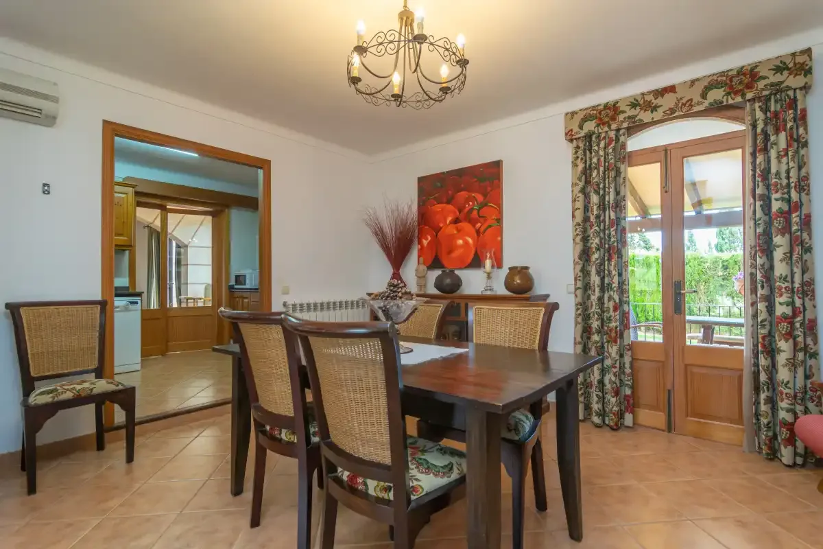 A dining room with a wooden table and chairs beneath a chandelier.