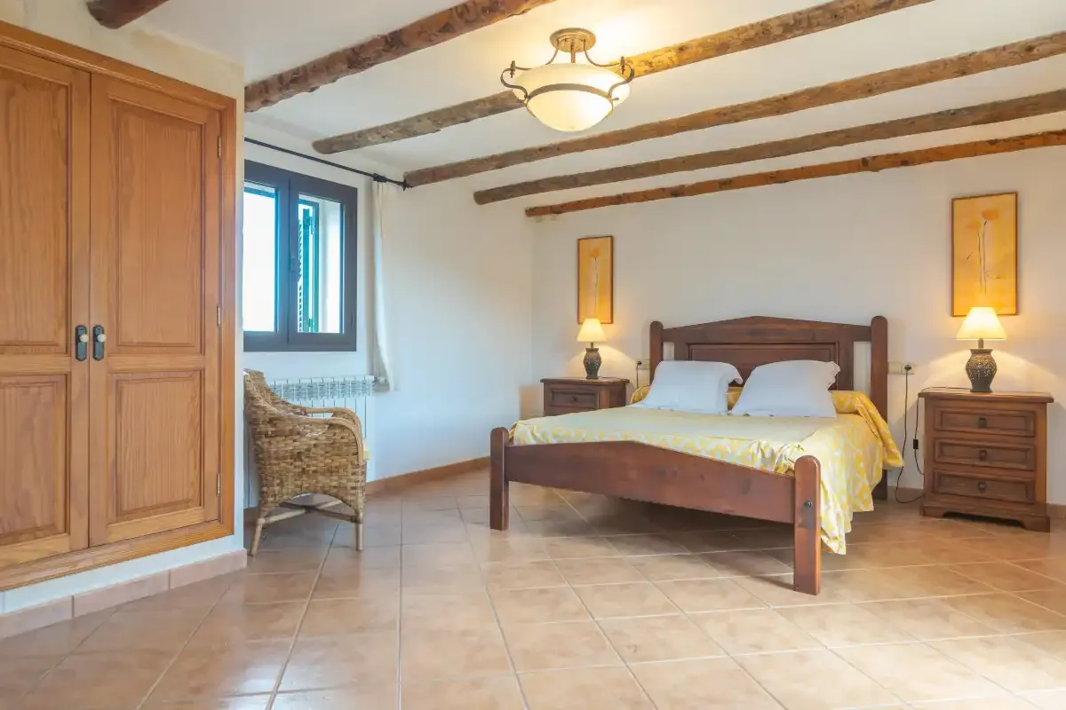 A bedroom with a wooden bed, bedside tables, and exposed ceiling beams.