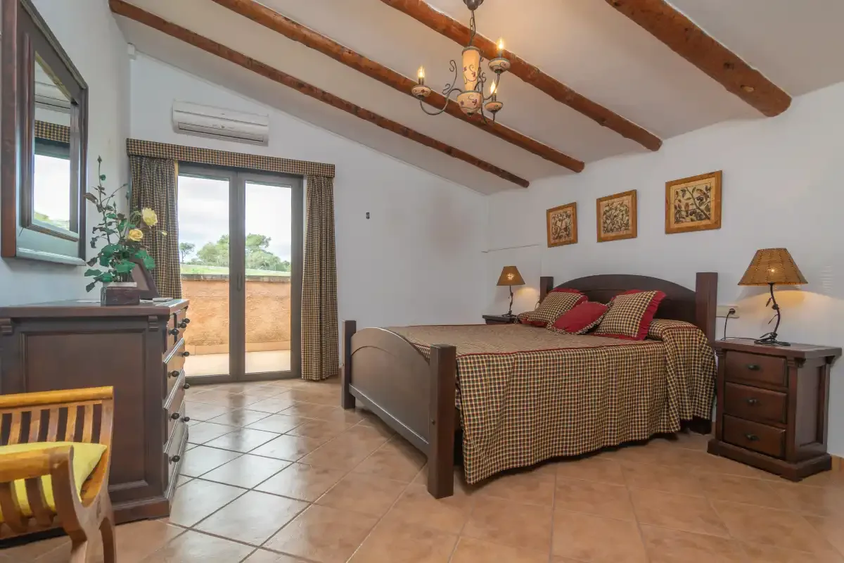 A bedroom with a double bed, bedside tables, and a glass door opening onto a terrace.