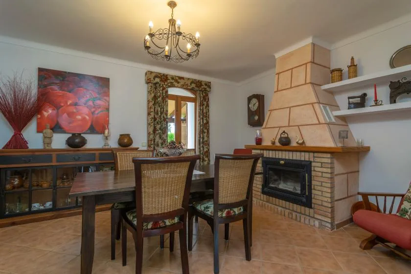 A dining room with a wooden table beside a brick fireplace.