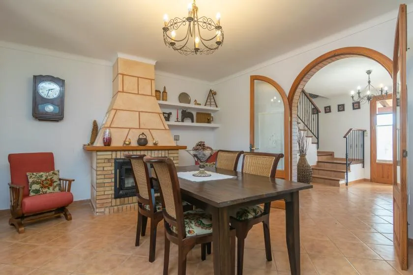 A dining room with a wooden table beside a brick fireplace.