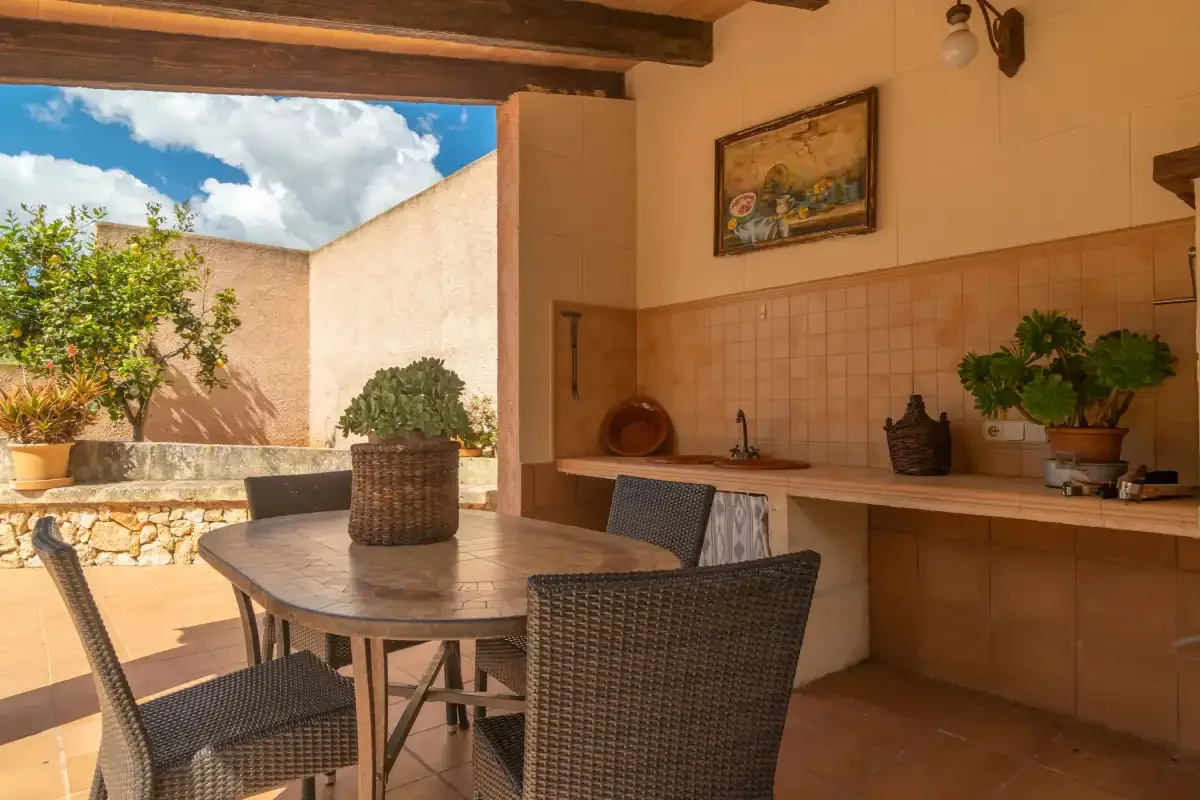 A covered outdoor dining area with a table beside a tiled counter.