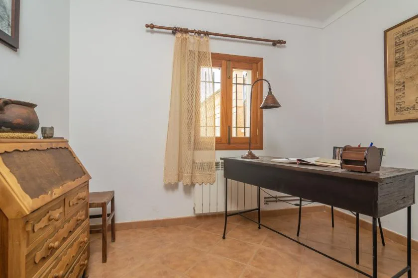 A study with a dark desk and a window with curtains.