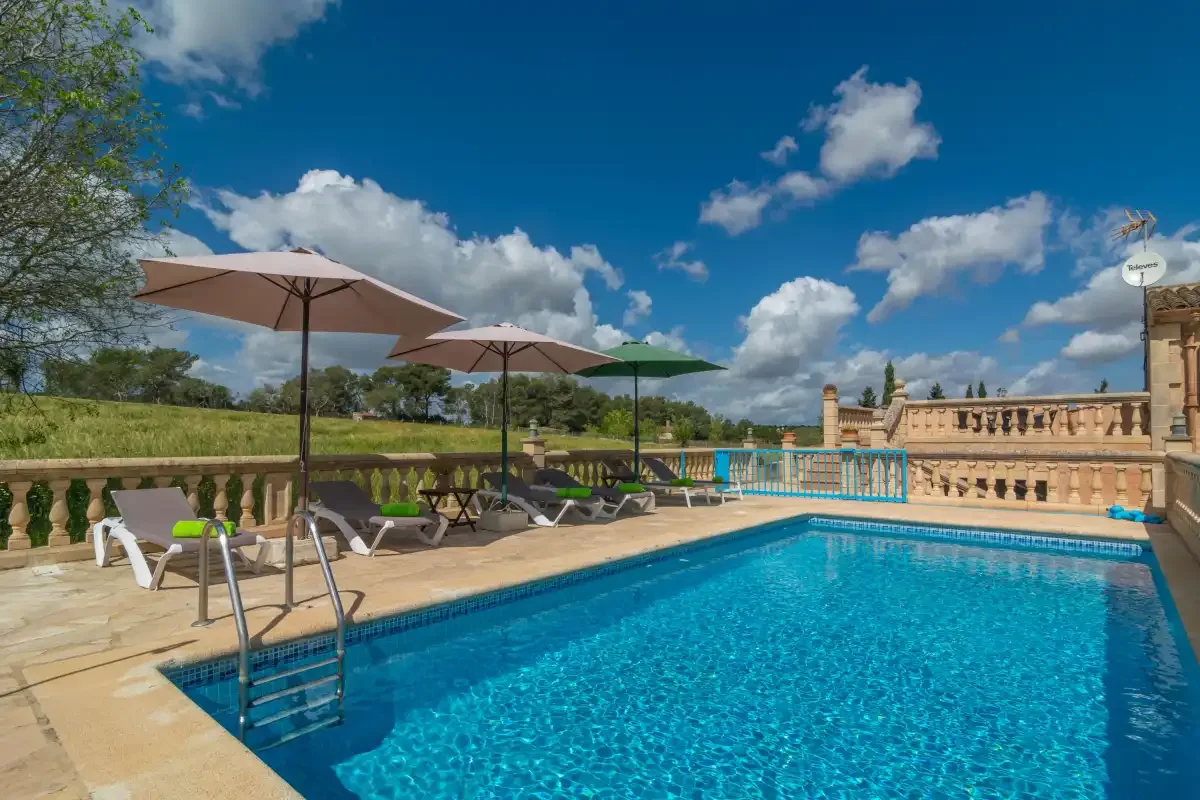 An outdoor swimming pool with lounge seating and umbrellas beside it.