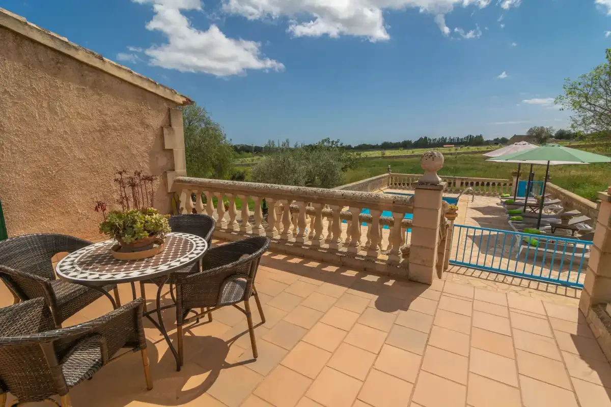 A sunny terrace overlooks a swimming pool and open countryside.