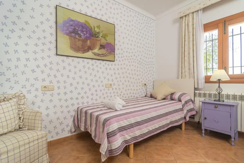A bedroom with a striped bed, patterned wallpaper, and a window.
