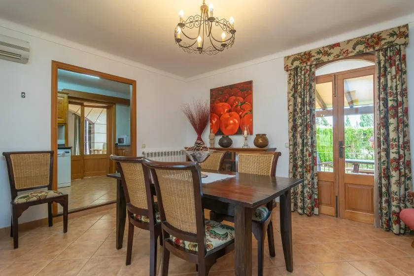 A dining room with a wooden table and chairs beside glass doors.