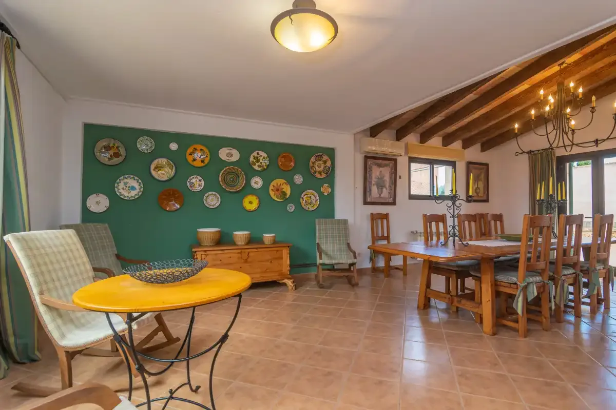 A dining and sitting room with a wooden table and decorative plates on the wall.