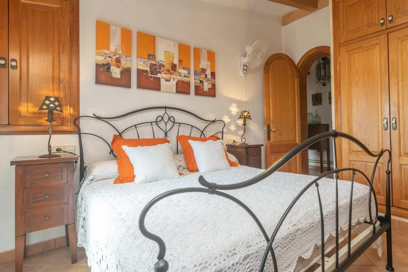 A bedroom with a metal bed, white bedding, and wooden cabinets.