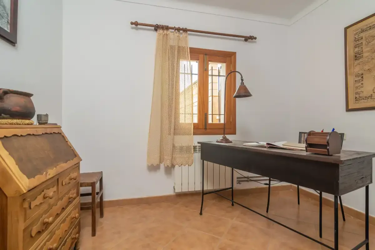 A room with a dark desk beside a curtained window.