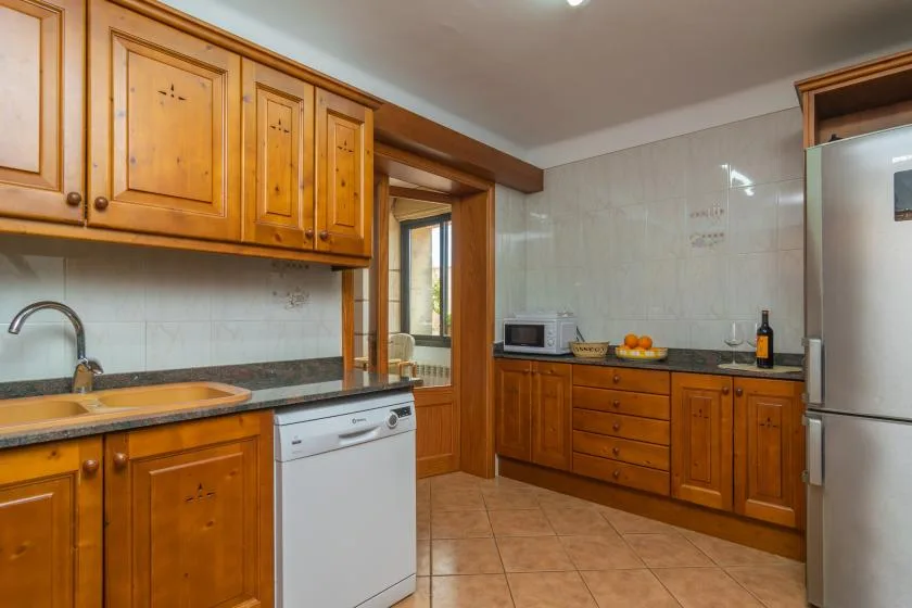 A kitchen with wooden cabinets, a dishwasher, and a refrigerator.