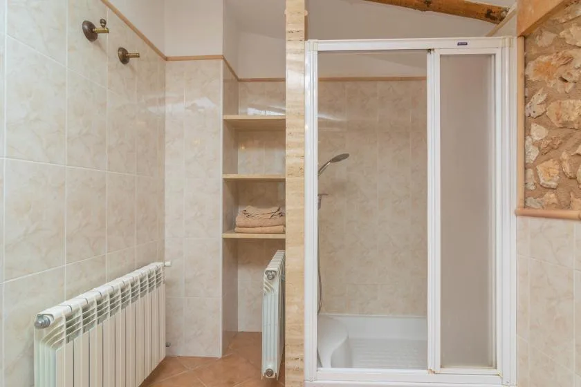 A tiled bathroom with a shower and built-in shelving.