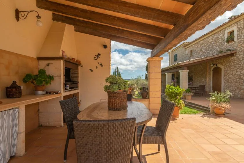 A covered outdoor dining area opens onto a sunlit courtyard with potted plants.