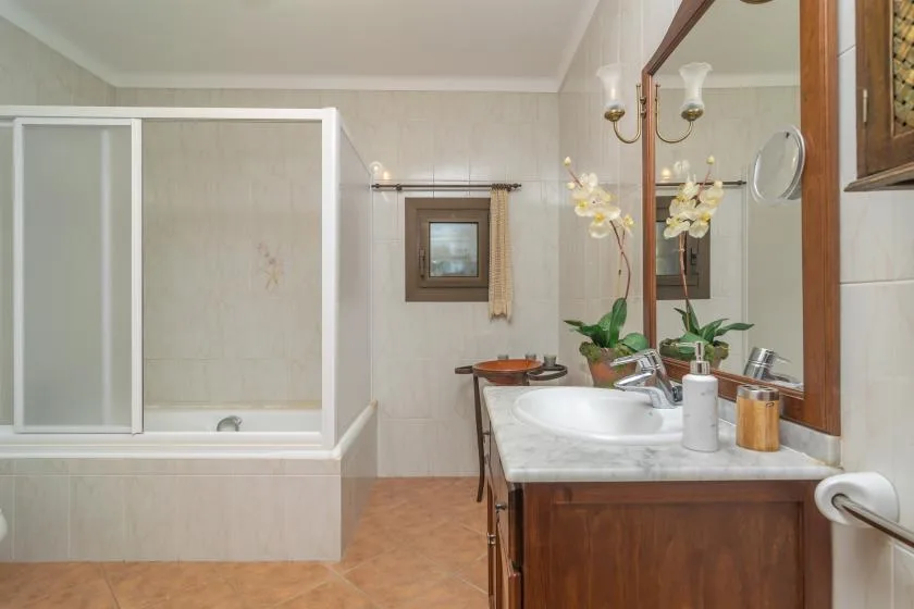 A bathroom with a bathtub, glass shower screen, and vanity with a sink.