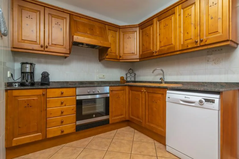 A kitchen with wooden cabinets, a countertop, and a built-in oven.