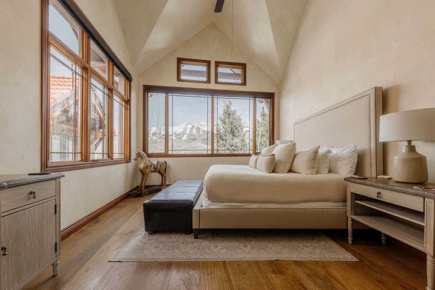 Un dormitorio luminoso con una cama, grandes ventanas y vistas a las montañas.