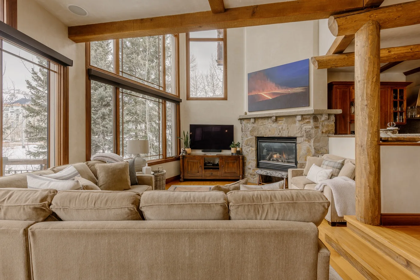 Una sala de estar con asientos, grandes ventanas y una chimenea de piedra.