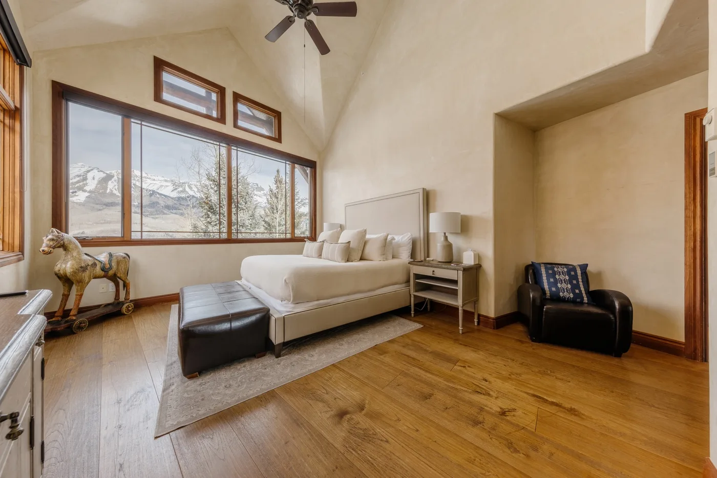 Una luminosa sala de estar con sofá seccional, grandes ventanas y vistas a las montañas.
