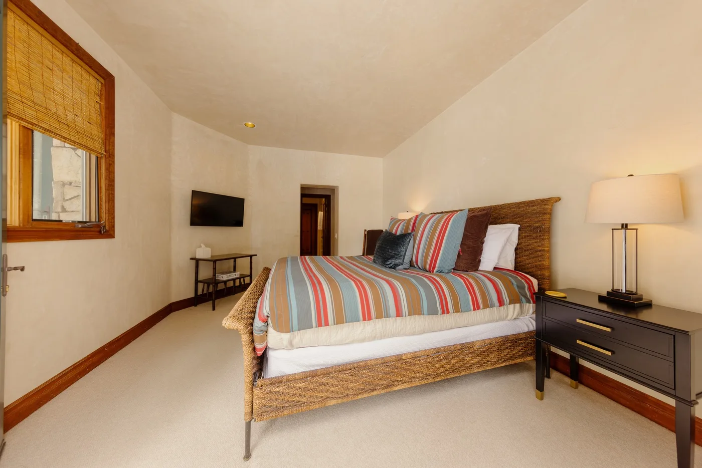 Un dormitorio con una cama a rayas y un televisor montado en la pared.