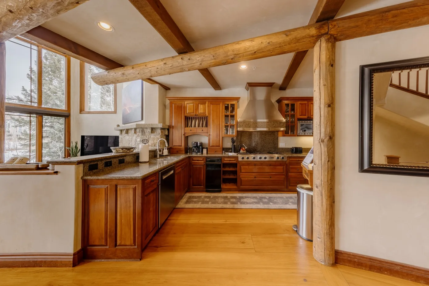 Una cocina con gabinetes de madera, una estufa grande y ventanas con vistas a los árboles.