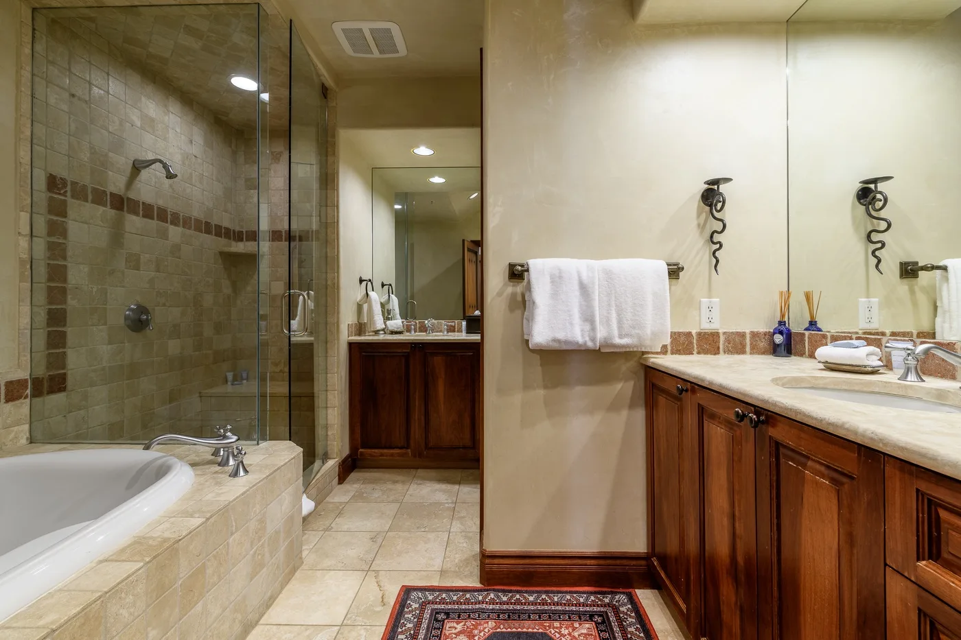 Un baño alicatado con bañera, ducha de vidrio y un tocador largo.