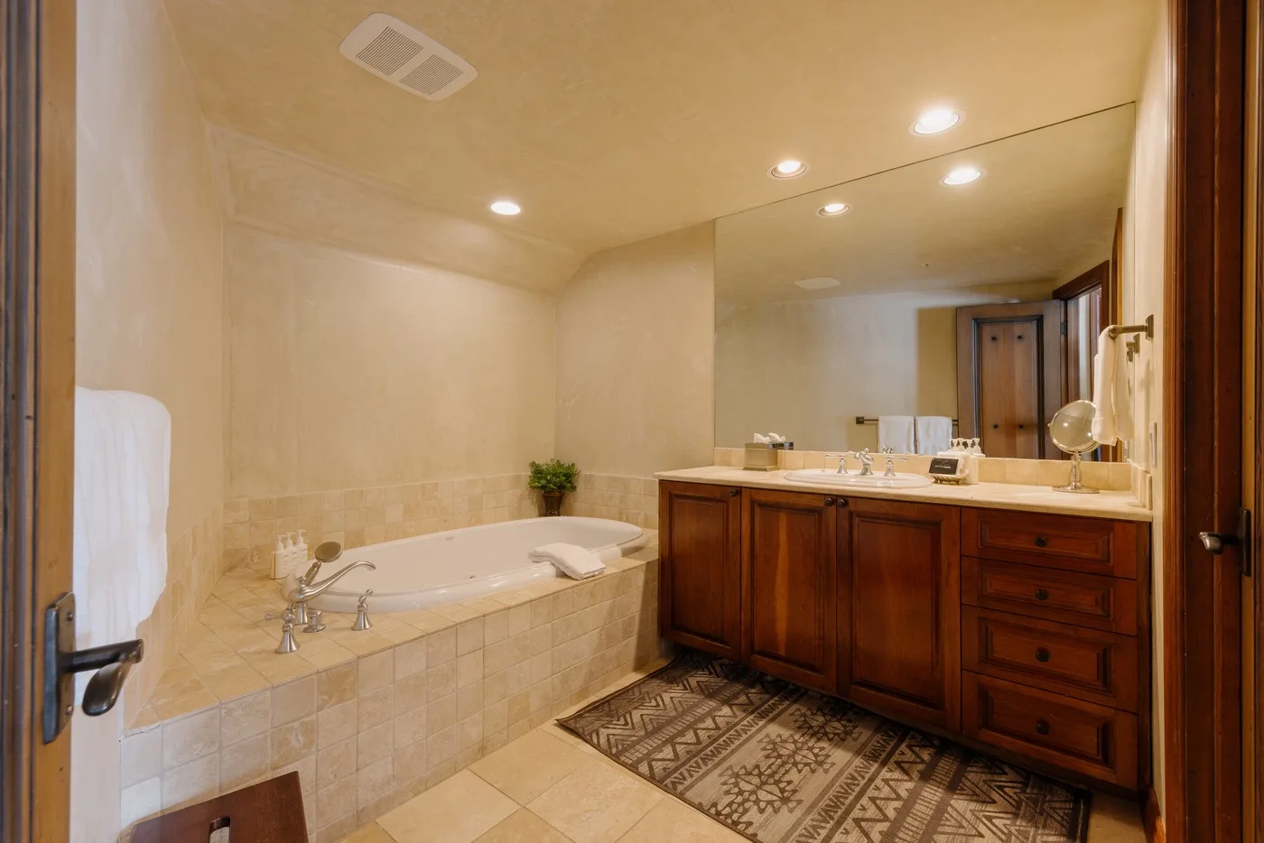 Un baño con bañera empotrada, lavabo con mueble y un gran espejo.